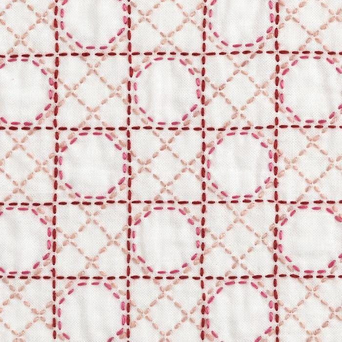 a close-up view of a fabric with a repeating pattern of pink and white circles and lines, creating a visually striking and intricate design.