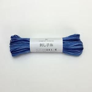 A spool of blue thread with Japanese text on it, lying on a white background.