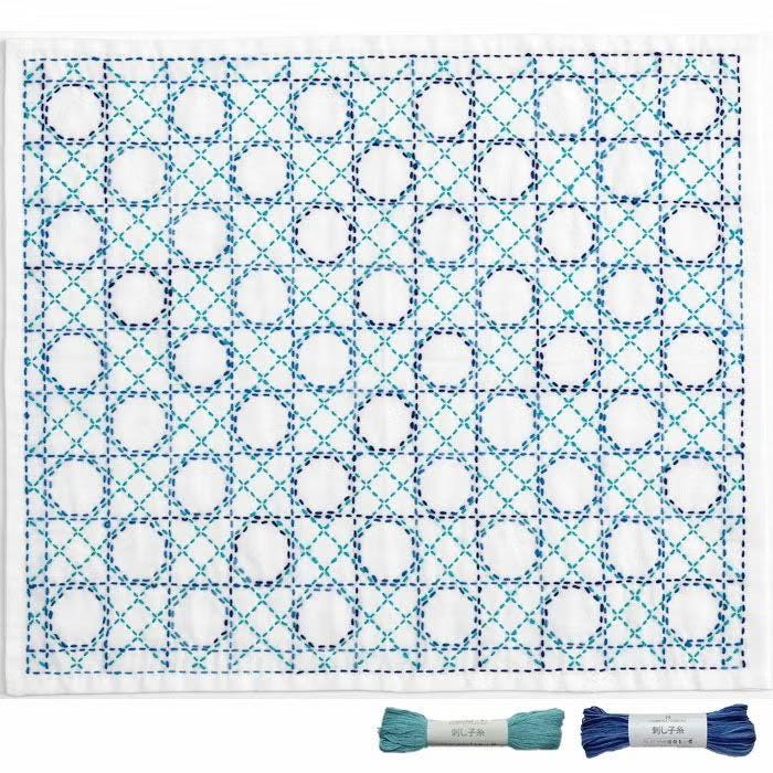 a square-shaped embroidery design with a repeating pattern of blue and white circles and lines. The design appears to be a quilt-like pattern, with the circles and lines creating a geometric and intricate design.