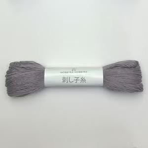 A spool of gray yarn with Japanese text on it, lying on a white background.