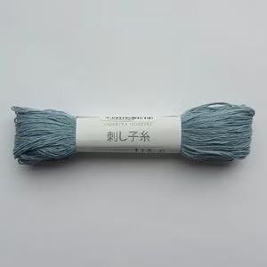 A spool of light blue yarn with a label in Japanese.