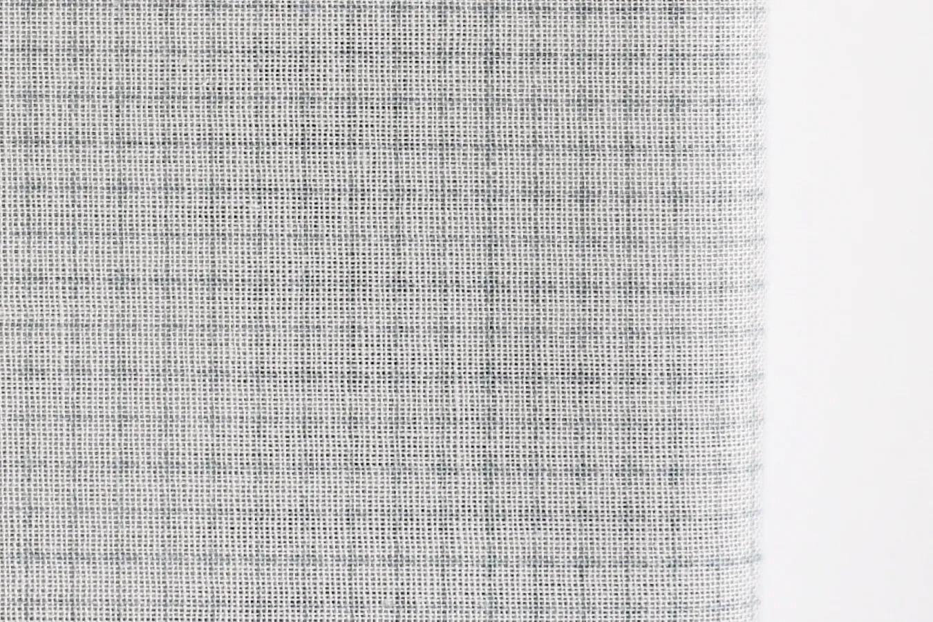 a close-up view of a fabric with a textured, woven appearance. The fabric appears to be a light gray or white color, with a pattern of small squares or lines that create a textured surface. The image does not contain any discernible objects or actions, and there are no specific actions or objects that can be described in detail.