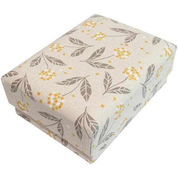 A rectangular gift box with a beige fabric pattern featuring leaves and flowers in shades of orange and yellow.