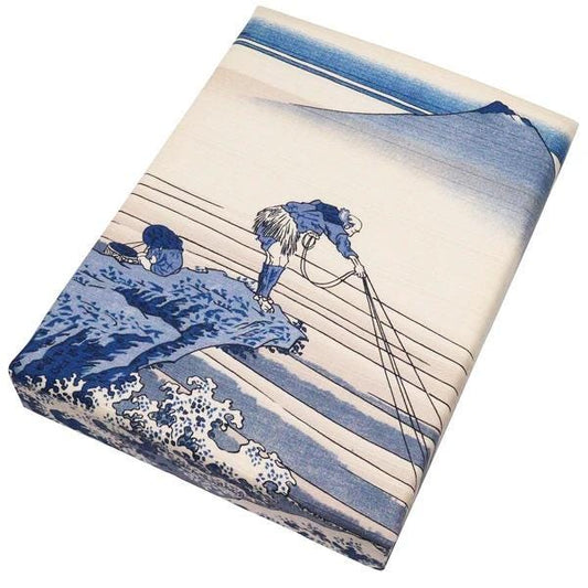 The image is a rectangular piece of fabric or paper with a blue and white design depicting a person standing on a cliff, overlooking a body of water.