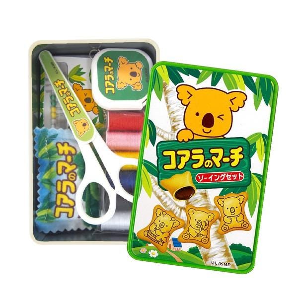 a set of children's art supplies, including a pair of scissors, a glue stick, and a small toy koala. The supplies are arranged in a box, with the scissors and glue stick placed together, and the toy koala depicted on the packaging.