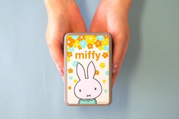 A pair of hands holding a small tin with a picture of a bunny and the word "miffy" on it.