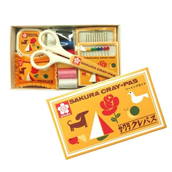 a sewing kit with various tools and accessories, including scissors, needles, and pins. The kit is presented in a box, and there is a label on the box that includes text and illustrations.