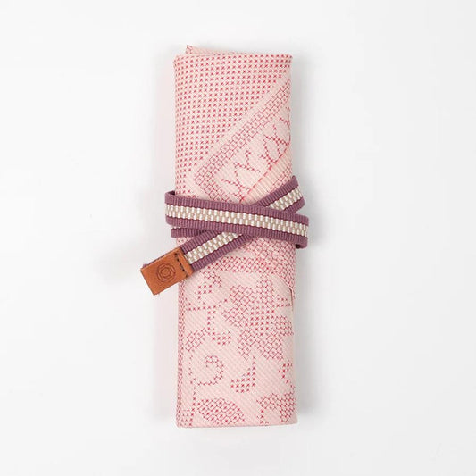 A pink and white patterned cloth rolled up and tied with a purple and white striped ribbon.