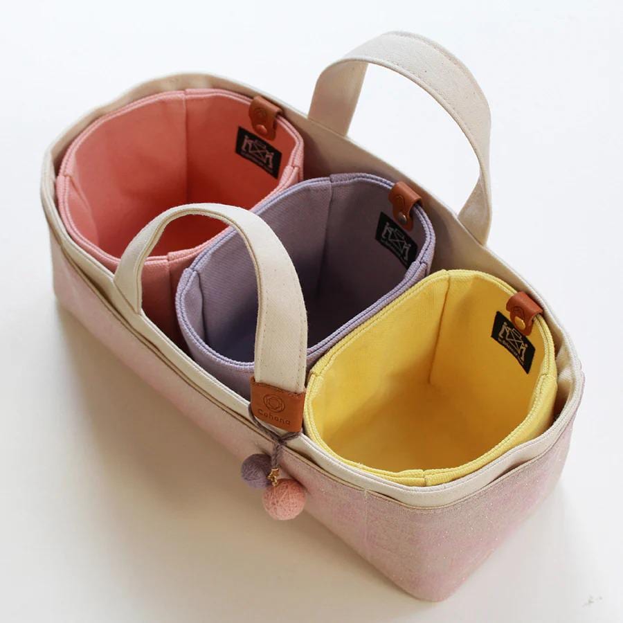 A pink tote bag with three compartments, each containing a different colored item.