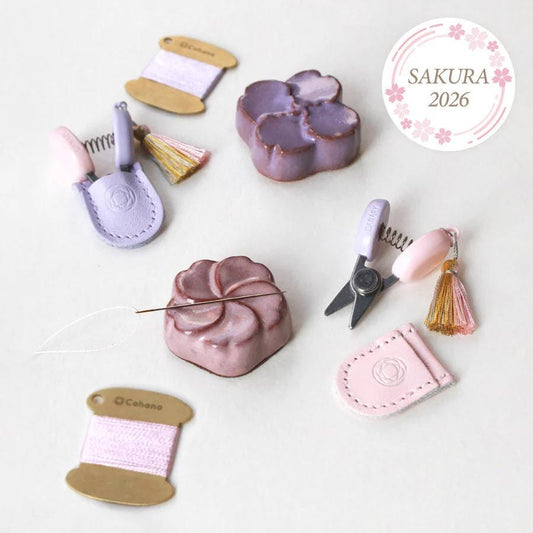 various sewing and crafting supplies, including a spool of thread, a pair of scissors, a keychain, and a small pink flower-shaped object.