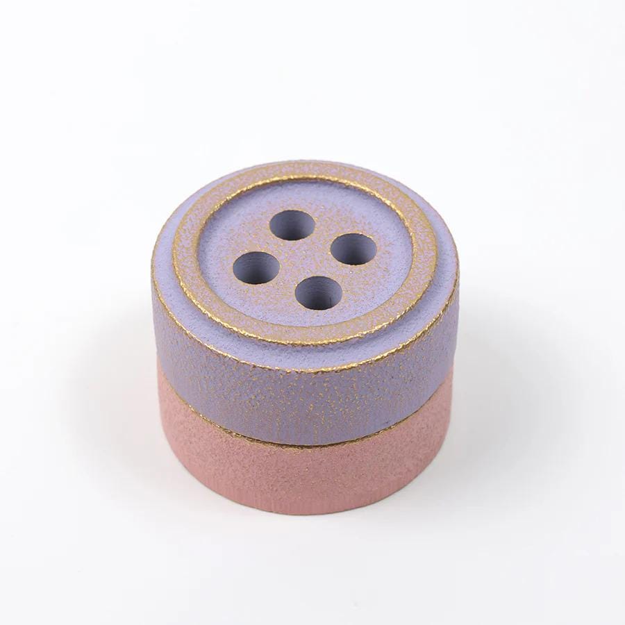 A purple button with gold trim is shown against a white background.