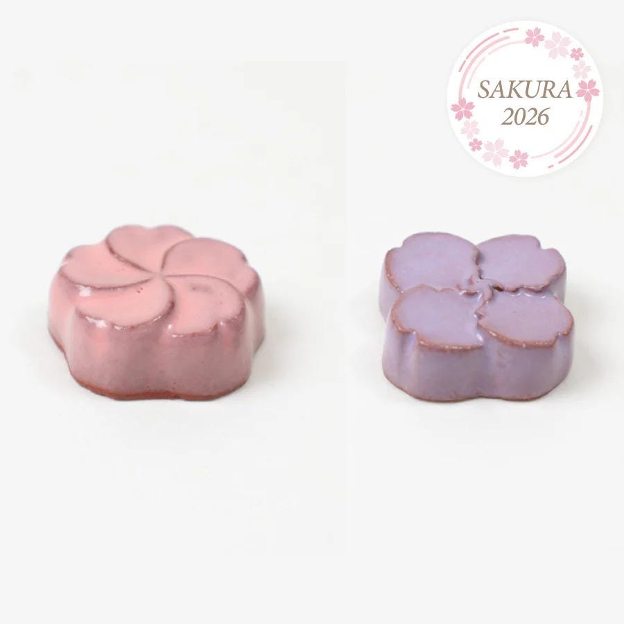 two flower-shaped chocolates, one pink and one purple, arranged side by side.