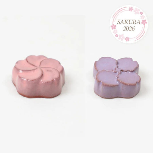 two flower-shaped chocolates, one pink and one purple, arranged side by side.
