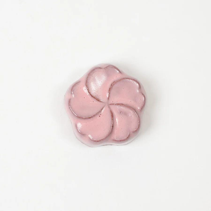 A single pink flower-shaped object is centered against a white background.