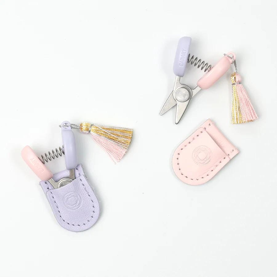 a pair of scissors with tassels and a keychain attached to them, placed on a white background.