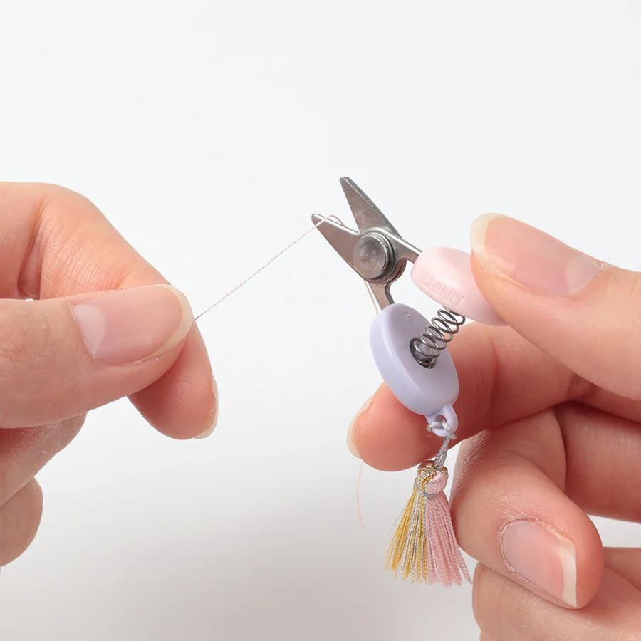 A pair of hands holding a pair of scissors and cutting a string.