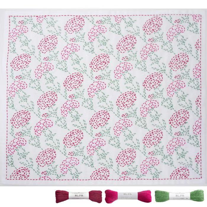 a square piece of fabric with a repeating floral pattern in shades of pink and green. The pattern consists of various flower shapes and leaves, creating a visually appealing and intricate design.