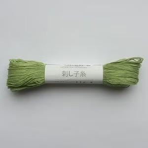 A spool of green yarn with Japanese text on it.