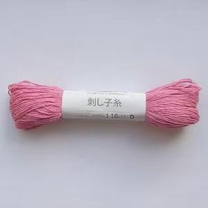A spool of pink yarn with Japanese text on it, lying on a white background.