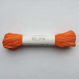 A spool of orange yarn with a label that includes Japanese text.
