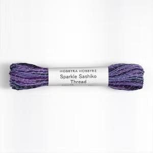 A spool of purple and black yarn labeled "Hobbyr Hobbyre Sparkle Sashiko Thread" is shown against a white background.