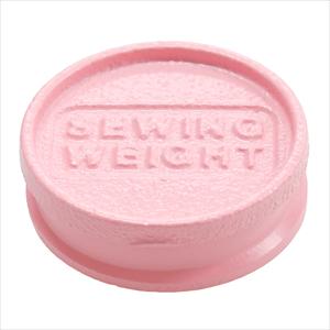 A pink, circular object with the text "Sewing Weight" embossed on it.