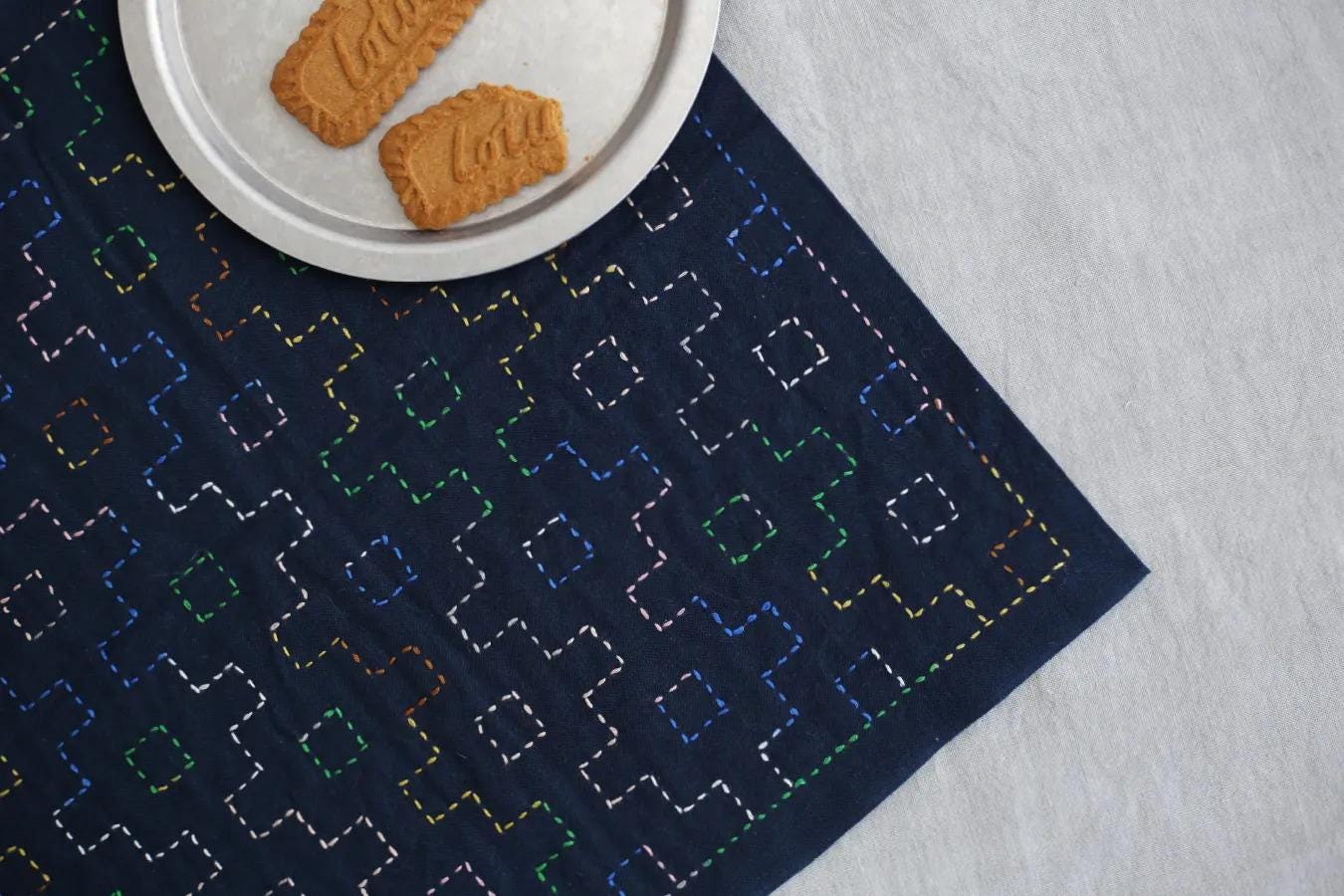 a plate with two cookies on a blue fabric with a geometric pattern, placed on a white surface.