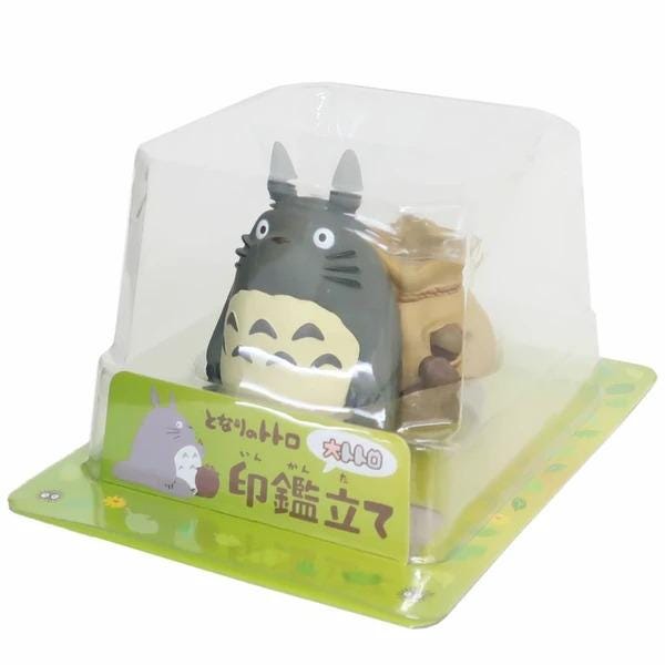 A toy figurine of a cat-like creature with a large head and small body, sitting inside a clear plastic packaging.