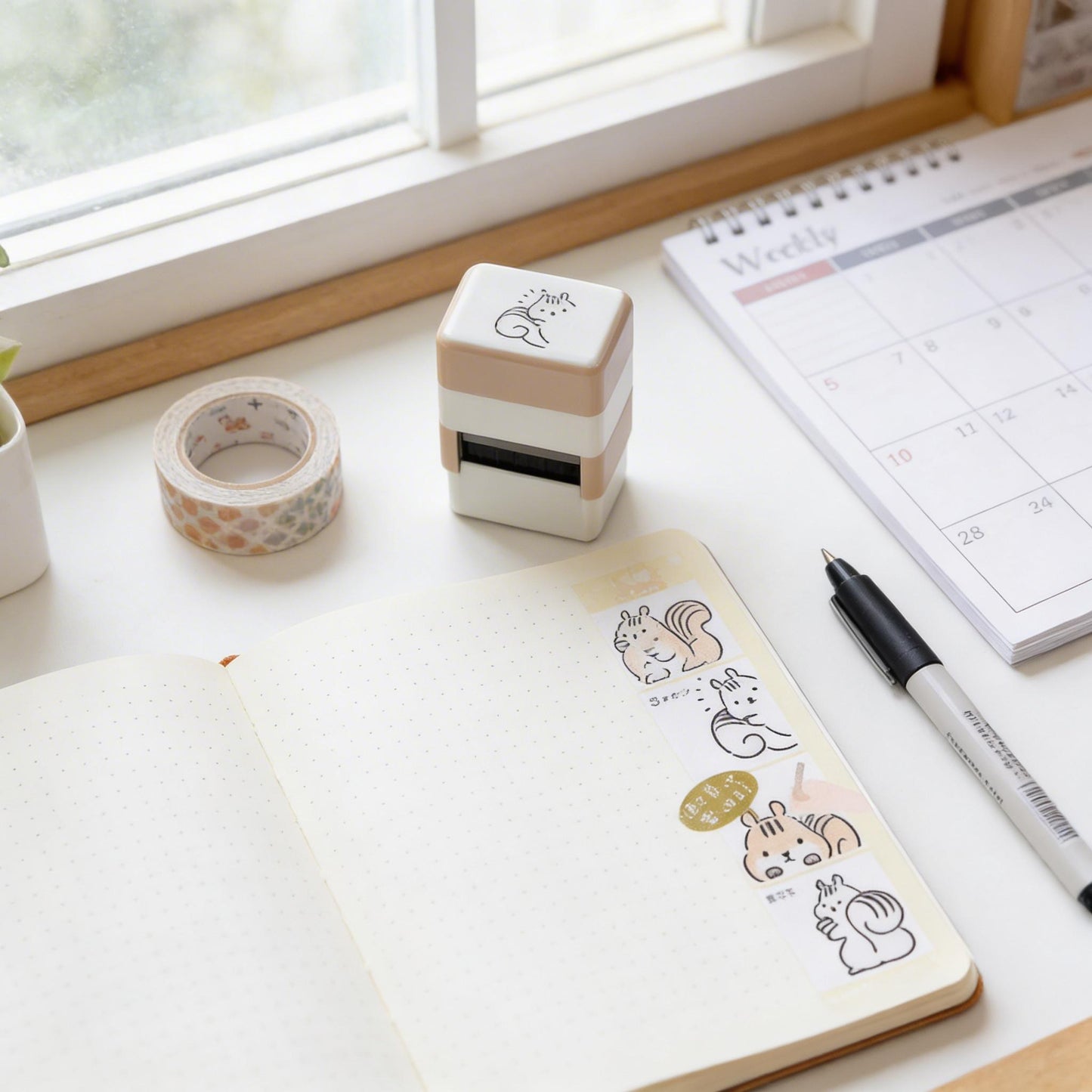 a desk with various office supplies and a calendar, including a stamp, a notebook, a pen, and a calendar.
