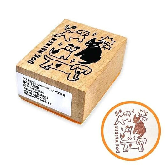 A wooden stamp with a black and white illustration of dogs and a dog walker on it, along with some text.