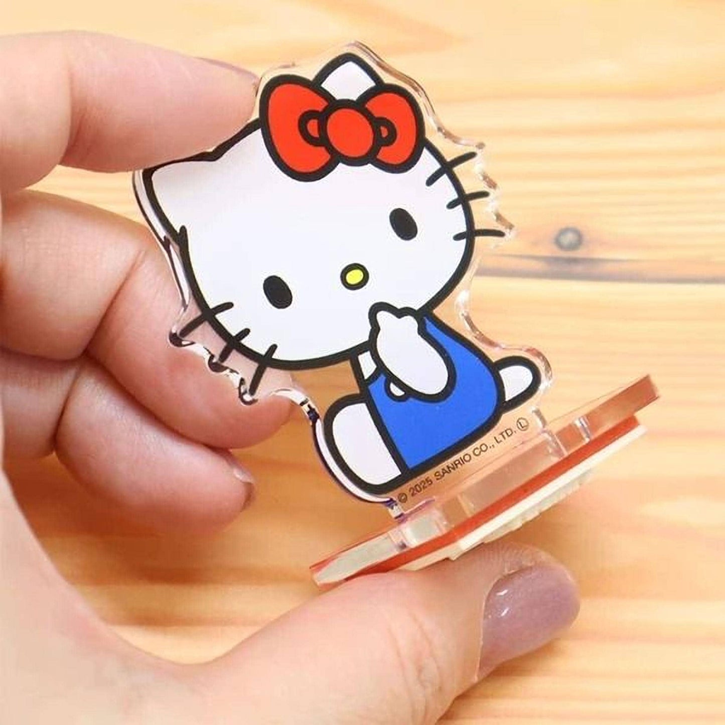 A hand is holding a Hello Kitty figurine, which is a character from the Sanyo animated series.