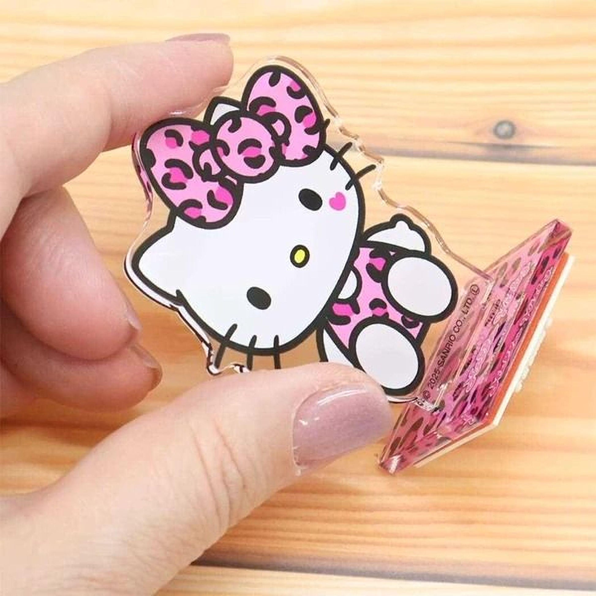 A hand holding a clear plastic object featuring a cartoon image of a Hello Kitty character.