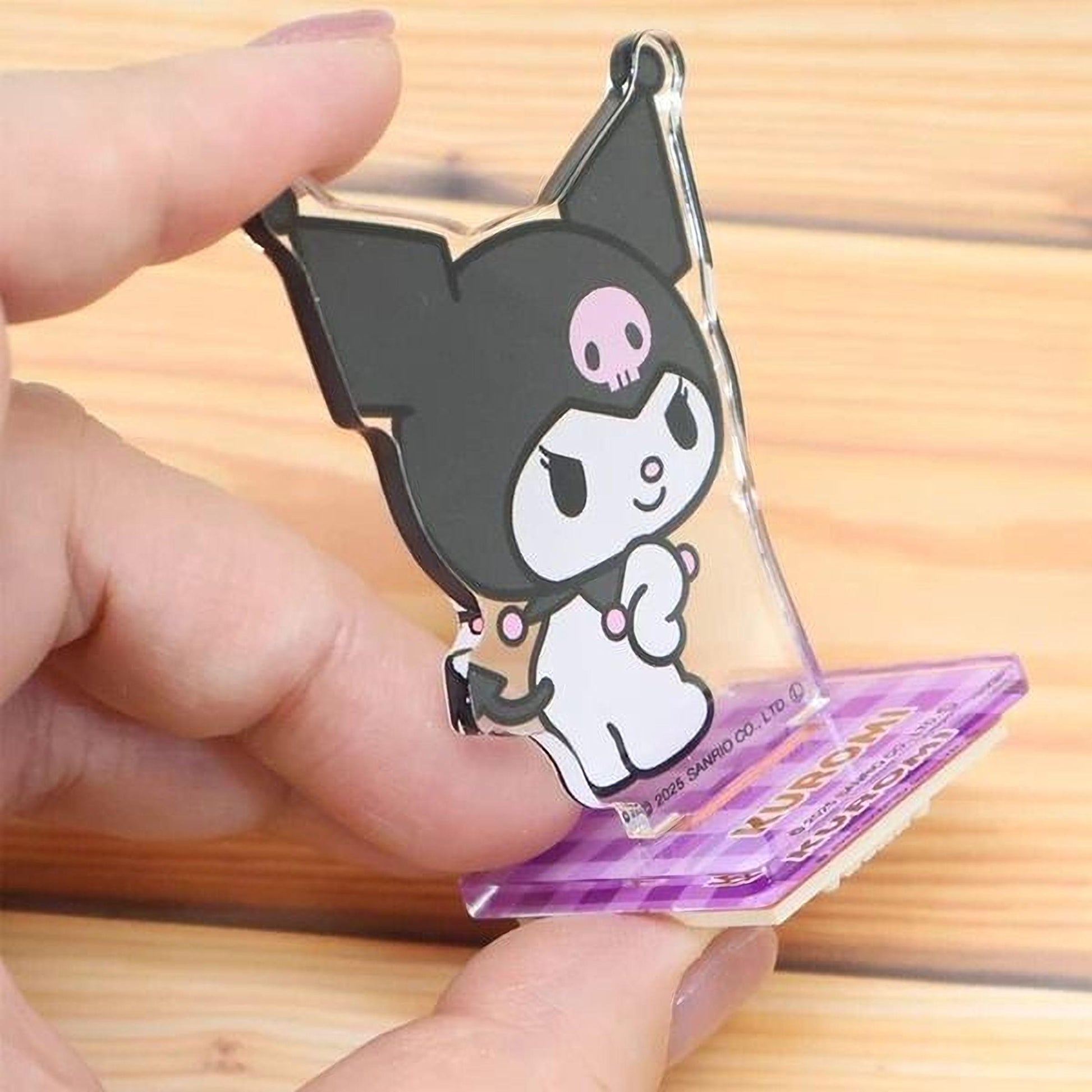 A hand holding a clear plastic keychain featuring a cartoon character with a black and white color scheme.