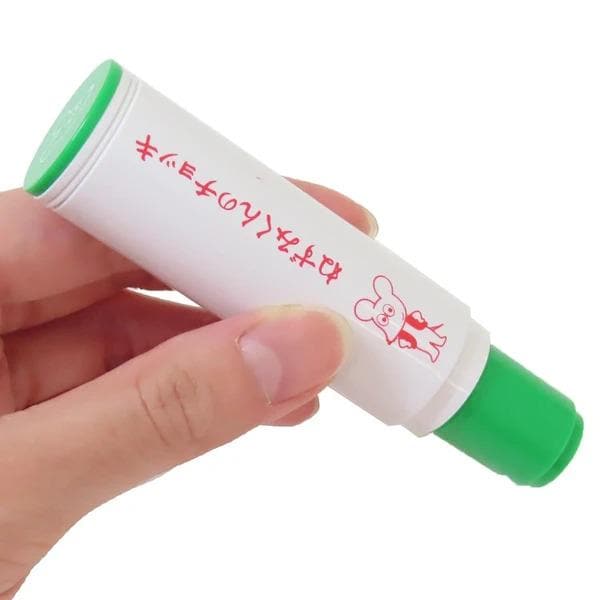 A hand holding a white marker with a green cap and red text on it.
