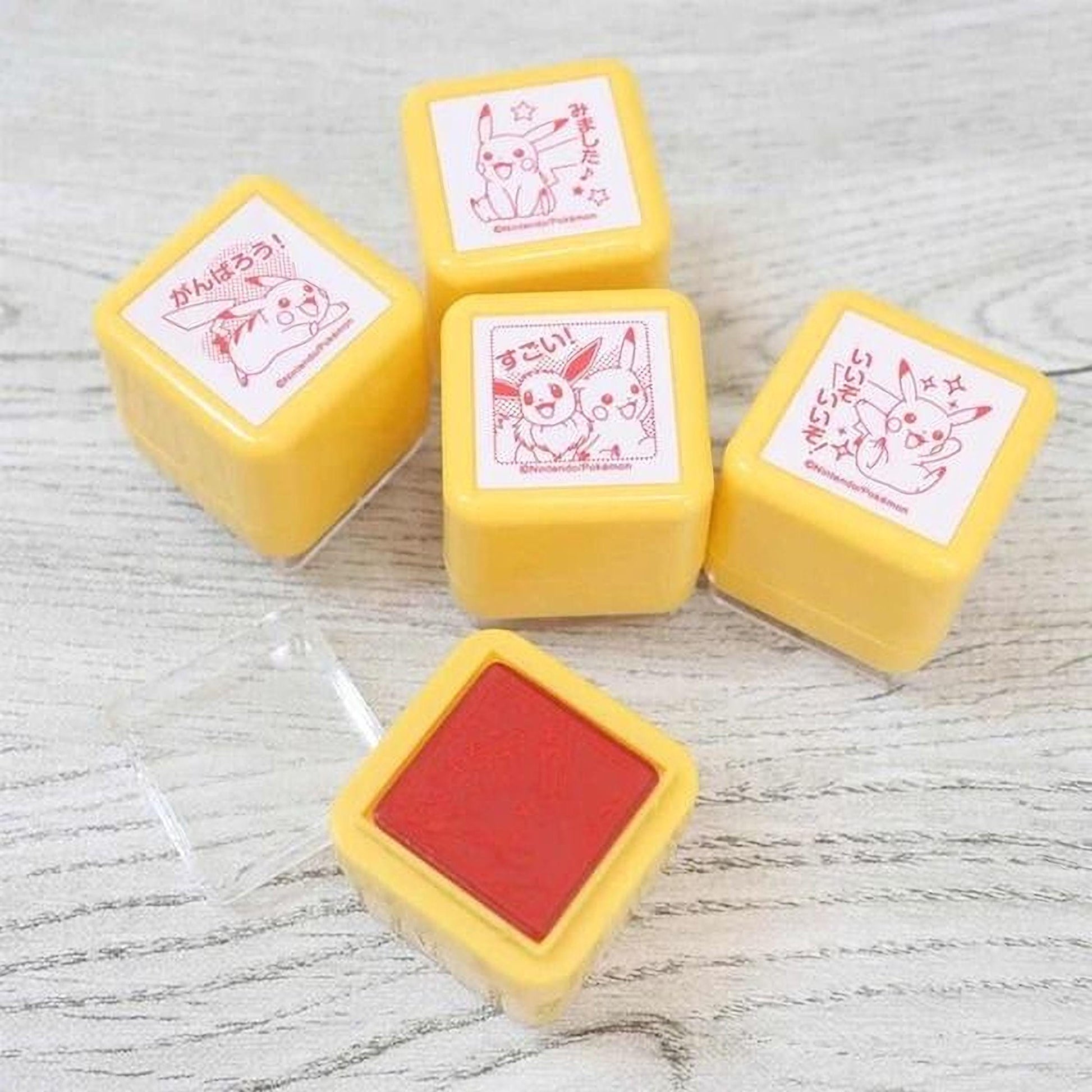 a collection of yellow and red Pokemon-themed stampers on a wooden surface.