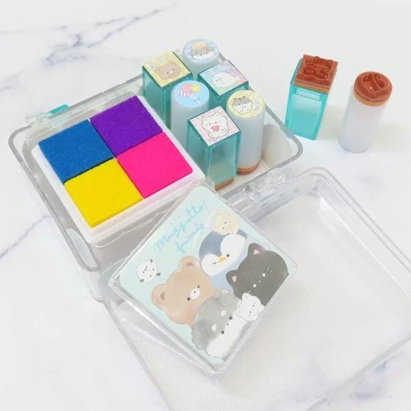 A clear plastic container filled with various colorful stamp blocks and a small picture frame containing cartoon animal illustrations.