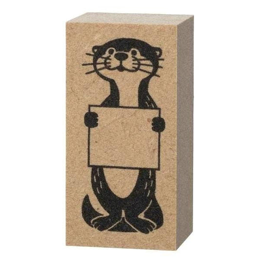 A block of wood with a black and white illustration of an otter holding a blank sign.