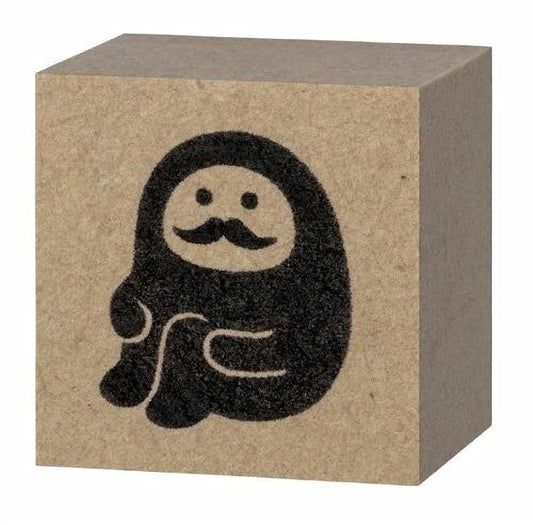 A block of brown cardboard with a black silhouette of a person with a mustache and goatee.