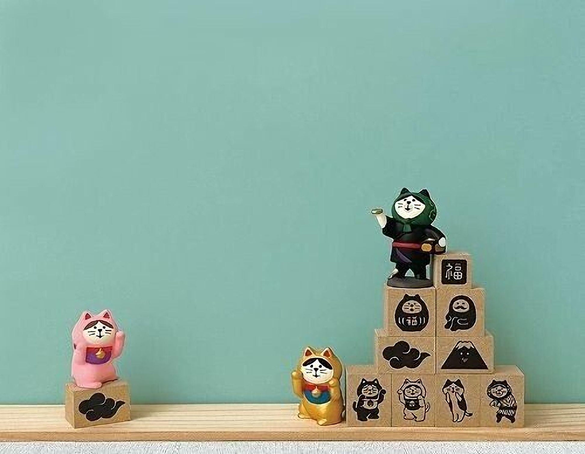 a collection of small figurines and blocks, including a pink cat figurine, a black cat figurine, and a stack of blocks with various cat designs on them.