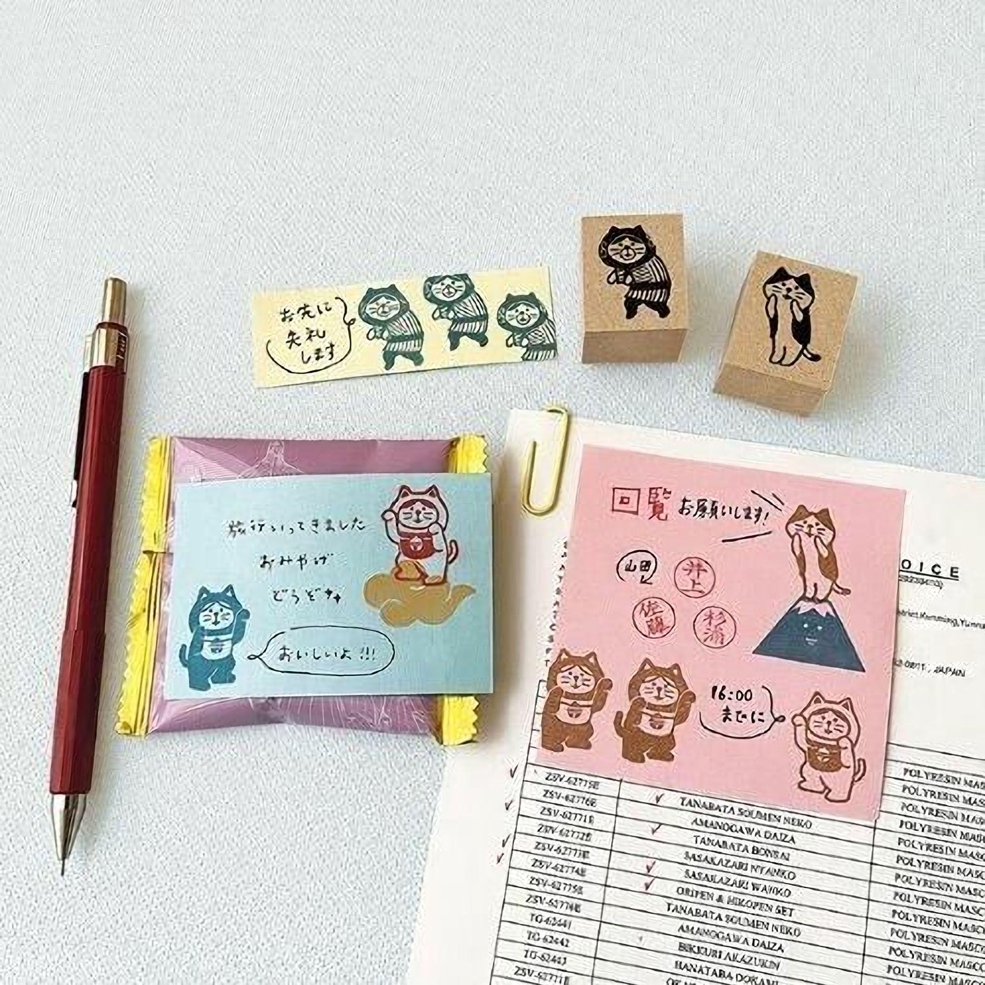 various items related to cats, including a pen, a book, and some cat-themed items such as stickers and blocks.