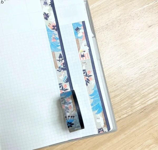 A piece of paper with a decorative pattern of colorful tape on it, placed on a wooden surface.