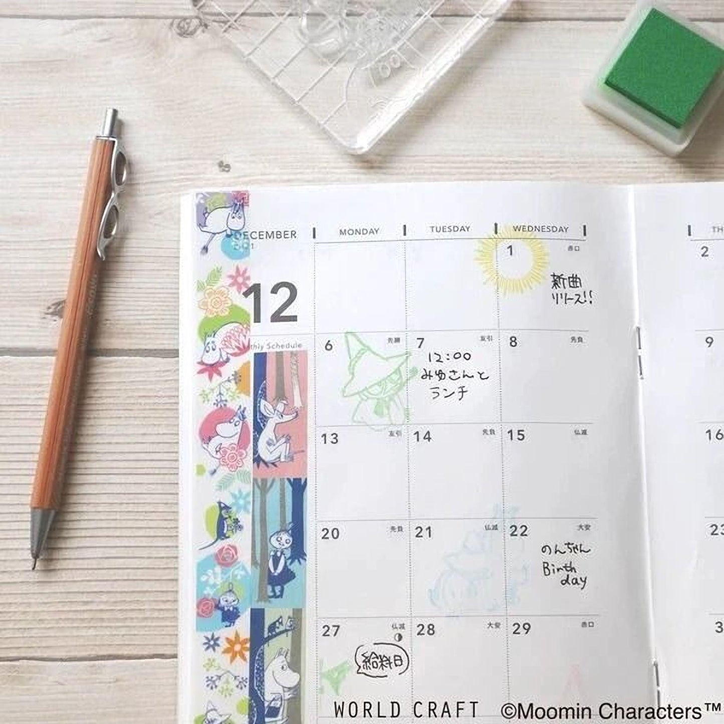 a calendar with colorful stickers and a pen on a wooden surface.