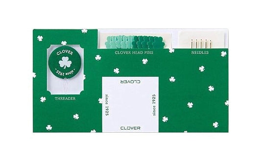 a green and white sewing kit with a shamrock design.