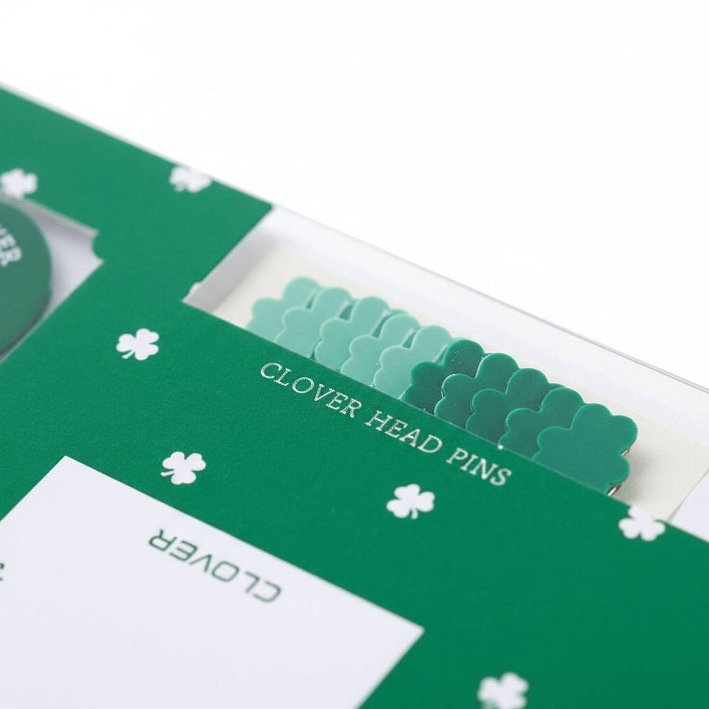 a close-up view of a green folder or binder with a row of green clover-shaped pins sticking out of it.