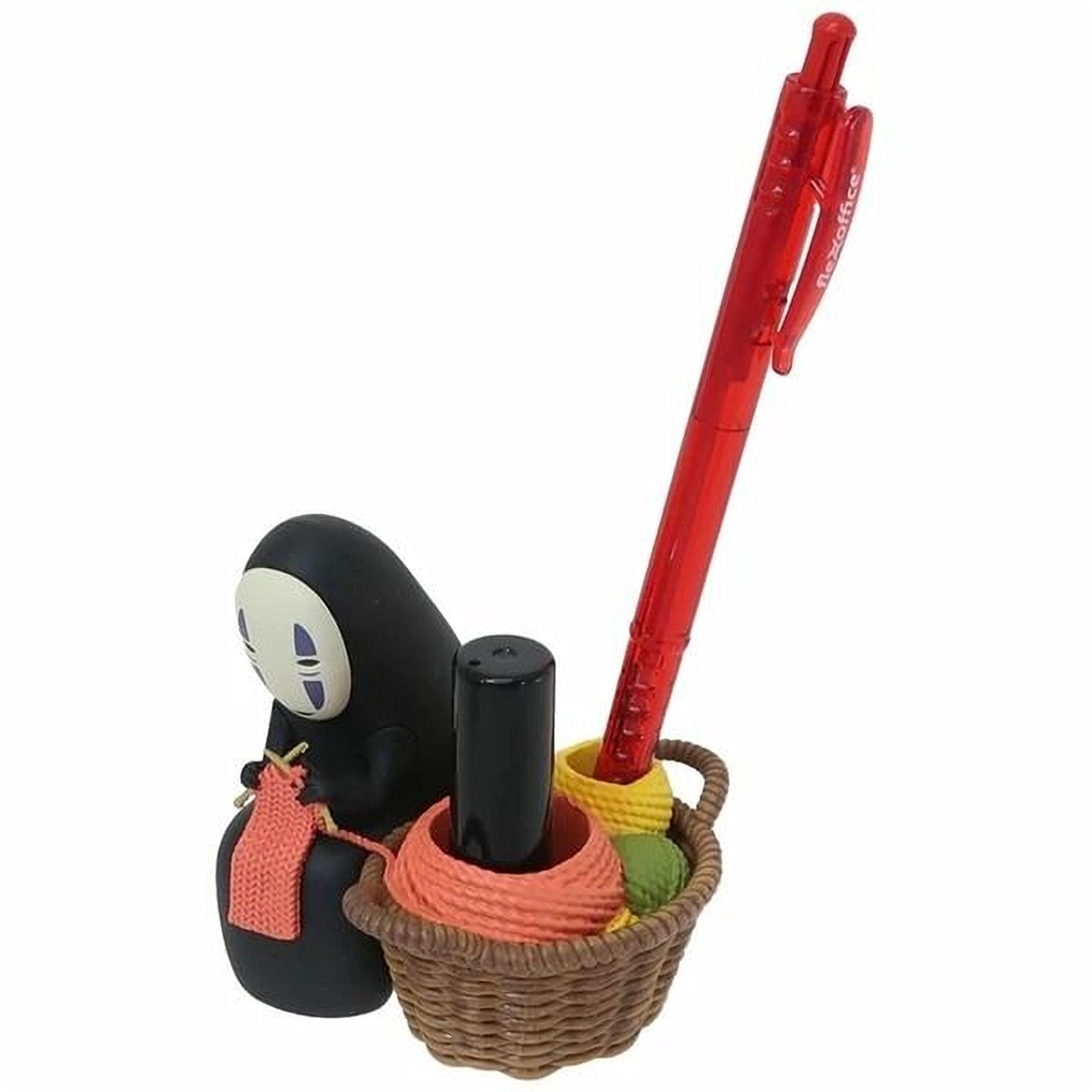 A figurine of a character with a black face and a basket containing various objects, including a red pen and a knitted item.