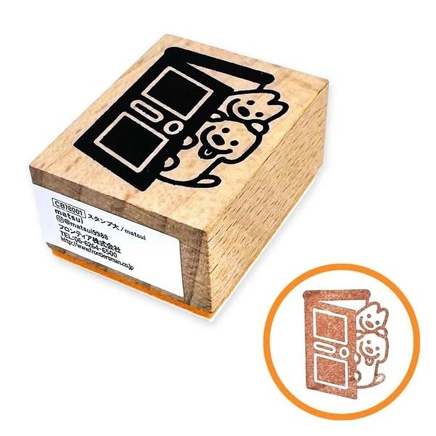 A wooden stamp with a black and white illustration of a door and two teddy bears on it, along with a label that includes text in Japanese.