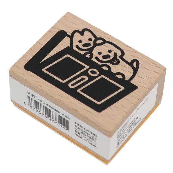 A wooden stamp with a black and white illustration of two dogs sitting on a table.