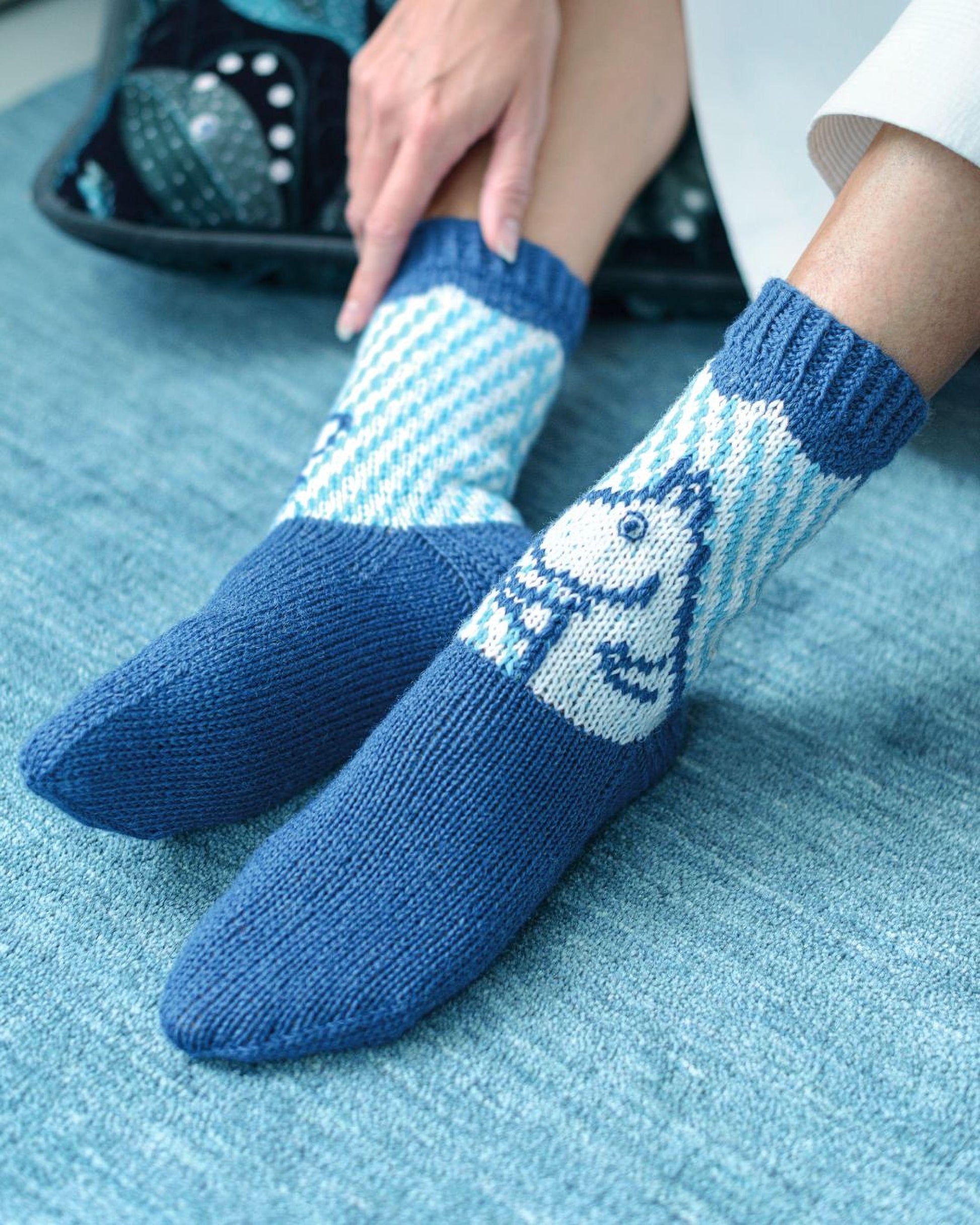A pair of blue and white patterned socks with a cartoon character design, resting on a blue surface.
