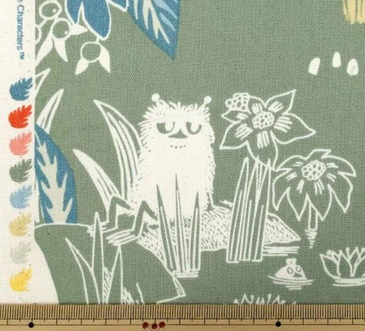 a close-up view of a fabric with a whimsical, cartoonish design. The design includes various elements such as a cat, flowers, leaves, and other abstract shapes. The fabric appears to be a piece of cloth or textile, with a ruler visible in the bottom right corner.