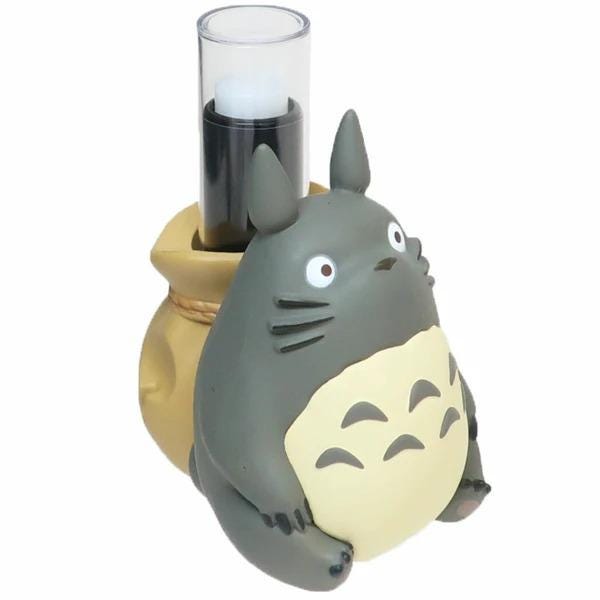 A gray and yellow toy resembling a cat or small animal, with a black candle holder in the background.